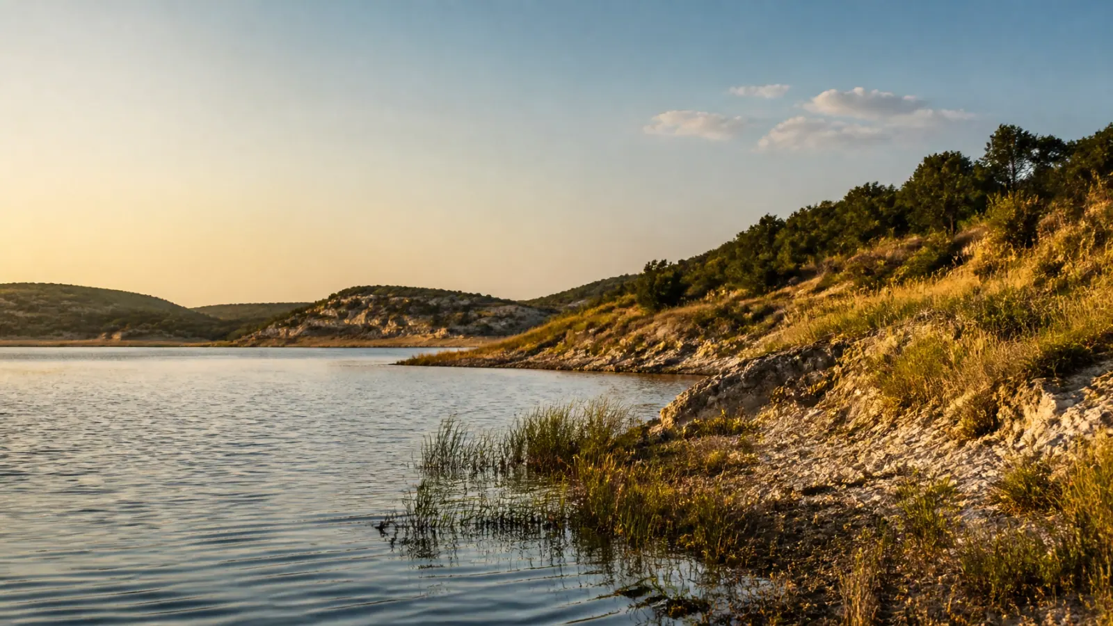 A Texas reservoir bordered by limestone and native grasses at golden hour